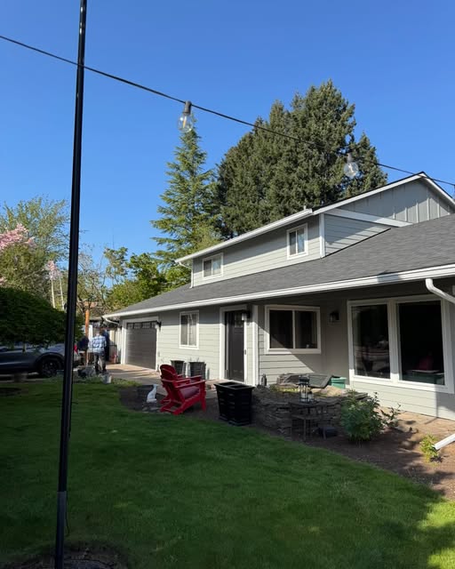 Single-story home finished exterior repaint in soft gray with mature landscaping
